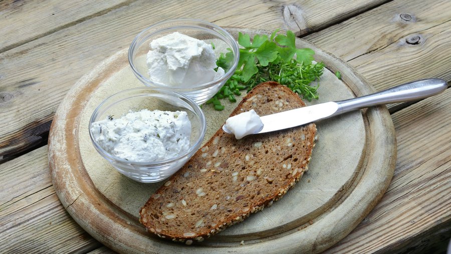 Frischkäse auf Lupinenbasis angerichtet auf einem Holzbrett mit einer Mehrkornbrotscheibe. © Fraunhofer IVV