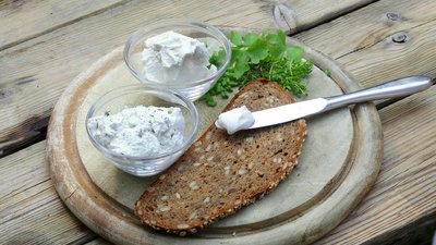 Frischkäse auf Lupinenbasis angerichtet auf einem Holzbrett mit einer Mehrkornbrotscheibe © Fraunhofer IVV  