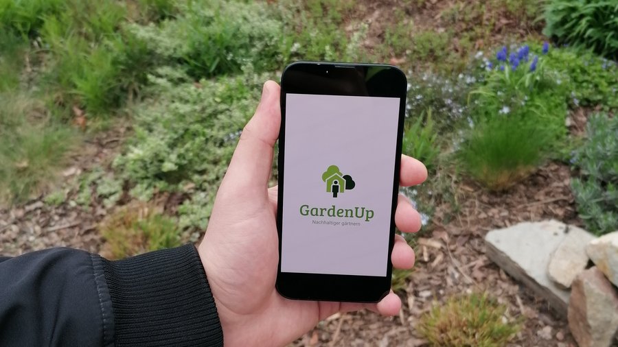 Smartphone in einer Hand vor einem Garten © HGU; snoopmedia