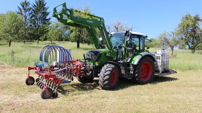 Ein Traktor mit Wasserstrahlgerät an der Front und Wasservorrat am Heck auf dem Feld © HfWU/Haußmann